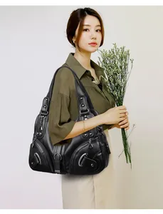 Detailed view of black pebbled leather tote with multiple zippers and metallic accents