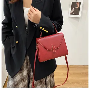 Deep red leather trapezoid tote bag with metal lock shown as a crossbody on a model
