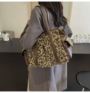 Leopard print canvas tote bag shown worn by a model in a trendy cafe setting