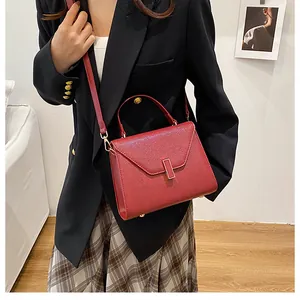 Close-up of red pebbled leather handbag with gold metal clasp and top handle for women