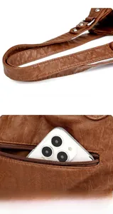 Détail du sac en cuir vintage marron montrant la poche zippée arrière avec un smartphone