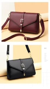 Detail of red and black leather crossbody bags with golden horseshoe buckles and V-flaps