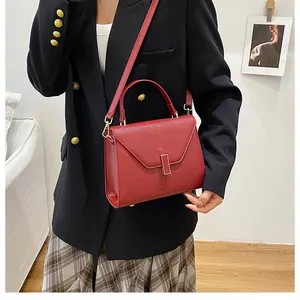 Detail of red pebbled leather tote bag featuring gold buckle and crossbody strap