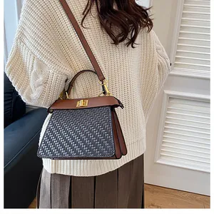 Detail of woven leather tote bag with classic metal twist lock and bicolor strap
