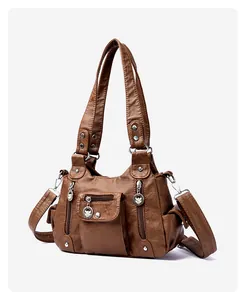 Detail of vintage brown PU leather handbag featuring embossed leaf zipper pulls and rivets