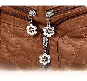 Détail du sac en cuir marron vintage avec surpiqûres losanges et zips en métal fleuris
