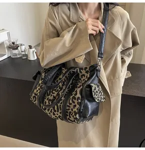 Leopard print canvas tote bag with black leather straps shown as a stylish crossbody bag
