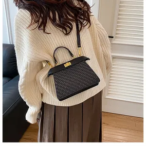 Detail of the black woven texture and gold metal bar closure on a luxury shoulder bag