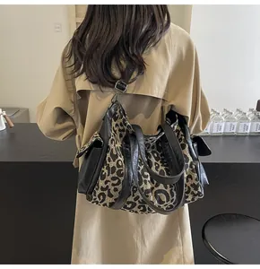 Detail of leopard print canvas tote bag with black faux leather trim and side flap pockets