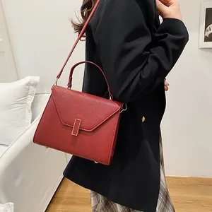 Red textured leather tote bag with gold buckle and adjustable strap for women