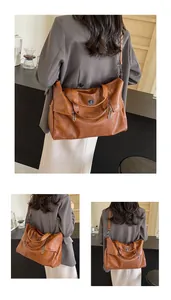 Detailed macro view of vintage brown leather tote bag with metallic emblem and handle