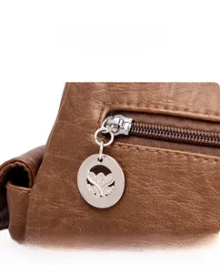 Detail of silver zipper and floral embossed metal puller on brown pebble leather bag