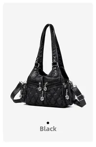 Détail du sac cabas en cuir matelassé noir avec breloques florales et fermetures éclair