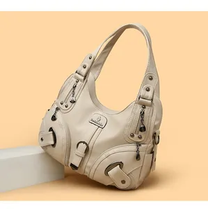 Close-up of cream-colored dumpling bag featuring lychee texture and metal rivet details