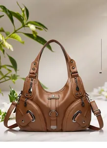 Close-up of brown litchi leather bag with decorative metal rivets and zippers