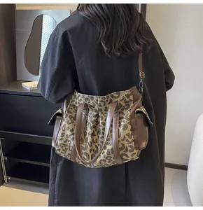 Detail of leopard print canvas tote bag with brown leather straps and side pockets