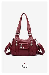 Detail view of red washed PU leather handbag with decorative silver metal zippers and charms