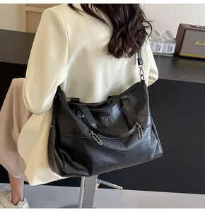 Detail of a large black vintage tote bag with lychee texture leather on a model outfit