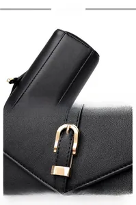 Detail view of black leather shoulder bag with fine stitching and gold round metal clasp