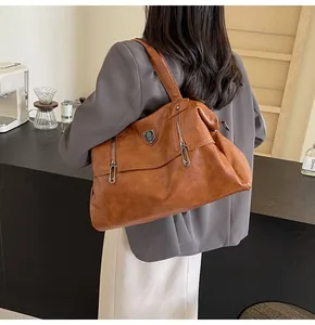 Brown vintage leather tote bag with side zippers and metal shield detail on model