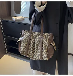 Detail of leopard print canvas tote bag with brown leather accents and large capacity