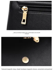 Detail view showing smooth golden metal zipper and textured magnetic snap on black leather bag