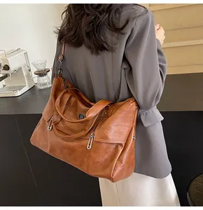 Detail of caramel brown faux leather tote bag featuring adjustable shoulder strap and metallic logo