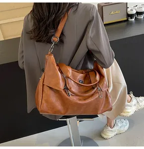 Retro brown soft leather tote bag detail with metal logo and adjustable shoulder strap