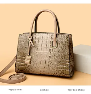 Detailed view of khaki crocodile pattern handbag with cowhide texture and gold buckle