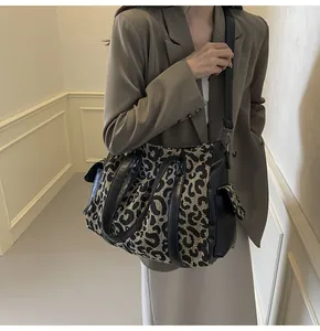 Detailed view of leopard print canvas tote bag with black side pocket on a model