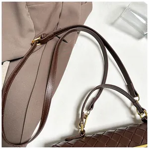 Dettaglio della trama in pelle intrecciata marrone scuro e finiture in metallo dorato sulla borsa