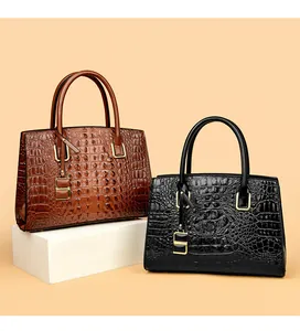 Detail of elegant crocodile-patterned handbags in brown and black with gold hardware