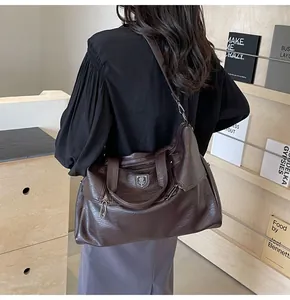 Detail of dark brown vintage faux leather tote bag with shield logo and adjustable strap