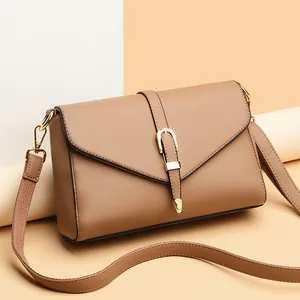 Minimalist brown faux leather crossbody bag with gold hardware on minimalist background