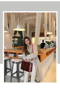 Borsa tote bordeaux in pelle goffrata coccodrillo con tracolla in un ambiente caffè caldo