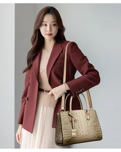 Fashionable champagne gold handbag with crocodile texture worn with a burgundy blazer