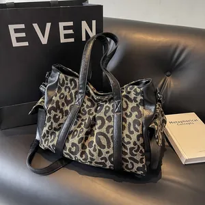 Large leopard print canvas tote bag with black leather straps on a sofa