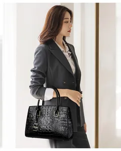 Detail of a chic black crocodile embossed handbag with golden hardware on a grey blazer suit