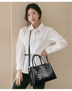 Modella asiatica con una borsa tote nera a trama coccodrillo e dettagli dorati