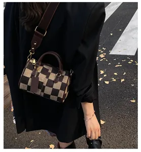 Classic checkered Boston bag with wide shoulder strap shown in an outdoor street setting