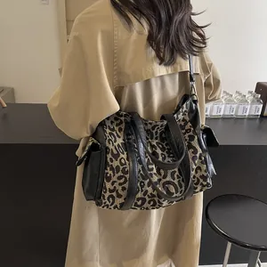 Leopard print canvas tote bag with black leather straps shown on shoulder for daily style