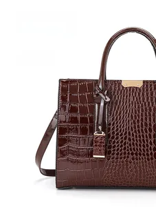 Dettaglio della borsa marrone con texture a coccodrillo e finitura lucida resistente