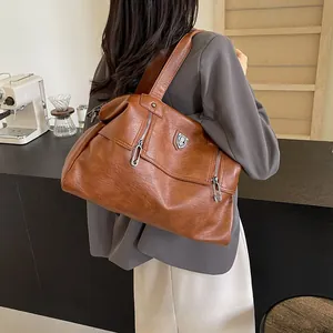 Vintage brown leather tote bag with side zipper and metal ring detail shown on a shoulder