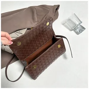Dettaglio ravvicinato della borsa marrone scuro con trama intrecciata e fibbia oro