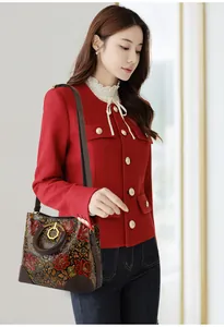 Detail view of vintage brown leather handbag with red embossed floral patterns on a model
