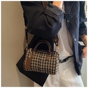 Detail of houndstooth boston bag with brown leather handles and wide shoulder strap