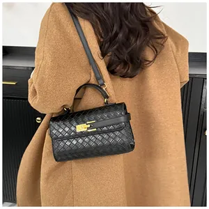 Dettaglio borsa intrecciata nera con chiusura dorata indossata su cappotto marrone