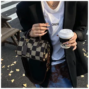 Close-up of retro checkered canvas Boston bag with leather handles and wide shoulder strap