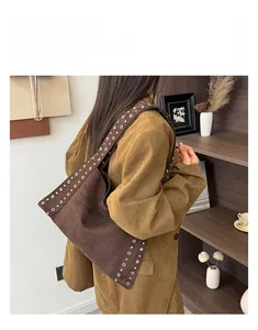 Détail d'un grand sac cabas en daim marron avec œillets métalliques et bandoulière
