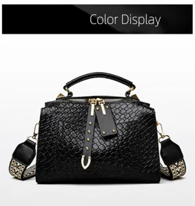 Detail of black crossbody bag with woven texture, gold hardware, and patterned strap